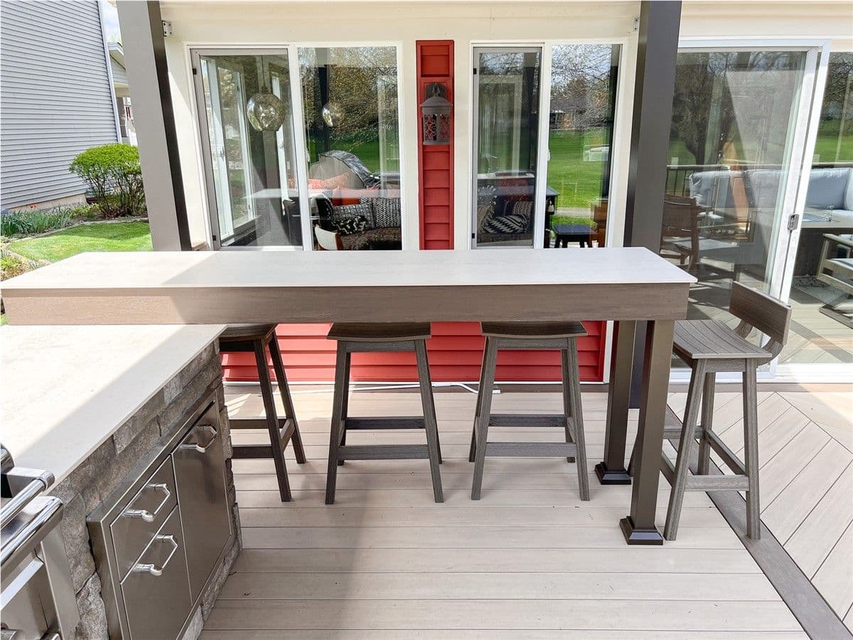 Bar-style seating with dark brown bar stools next to an outdoor kitchen on a deck.